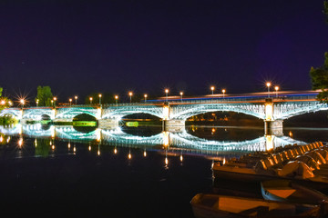 Fototapeta na wymiar eRiver crossing illuminated bridge, and bask in the foreground.