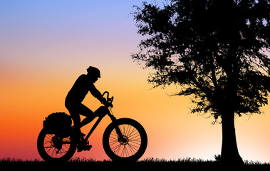 Fototapeta premium Silhouette man and bike relaxing on blurry sunrise sky background.