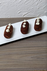 Potato cakes. Decorated with cream flowers. Lie on a white rectangular plate. Against the background of white wall with decorative plaster.