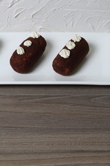 Potato cakes. Decorated with cream flowers. Lie on a white rectangular plate. Against the background of white wall with decorative plaster.