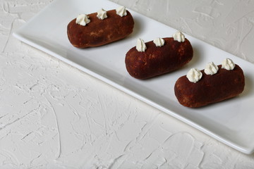 Potato cakes. Decorated with cream flowers. Lie on a white rectangular plate. Against the background of white wall with decorative plaster.