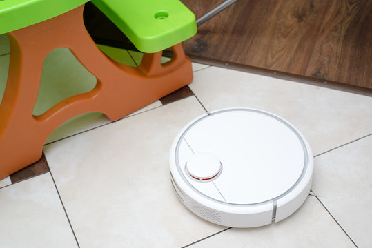 Robotic Vacuum Cleaner On Ceramic Tile Floor In Kitchen.