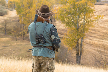 Hunter with a hat and a gun in search of prey in the steppe	