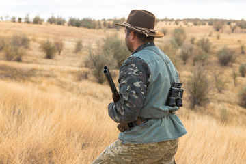 Hunter with a hat and a gun in search of prey in the steppe	