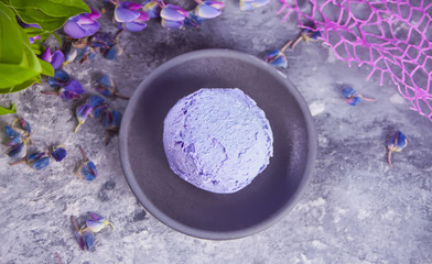 Obraz na płótnie Canvas Gray plate with purple lilac ice cream on the dark gray background decorating lupins