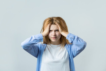 Emotional portrait of a red-haired girl on a gray background, stormy emotions, business concept.	