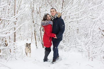 The guy and the girl have a rest in the winter woods. Husband and wife in the snow. Young couple walking in winter park