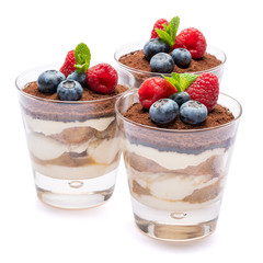 Classic tiramisu dessert with blueberries and raspberries in a glass isolated on a white background with clipping path
