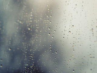 Raindrops on the surface of window glass with a blurred background.