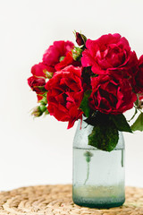 Fototapeta premium Stunning composition of colorful roses in a vase on a wicker napkin