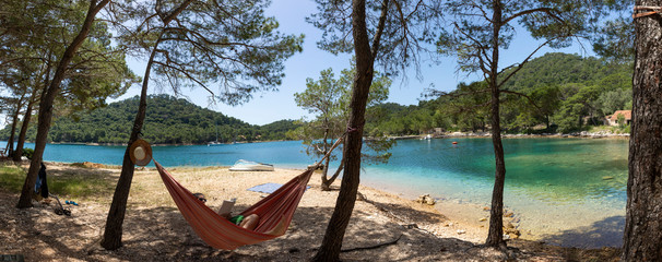 Woman relaxing in the hammock on a hot sunny day on the island lastovo, croatia
