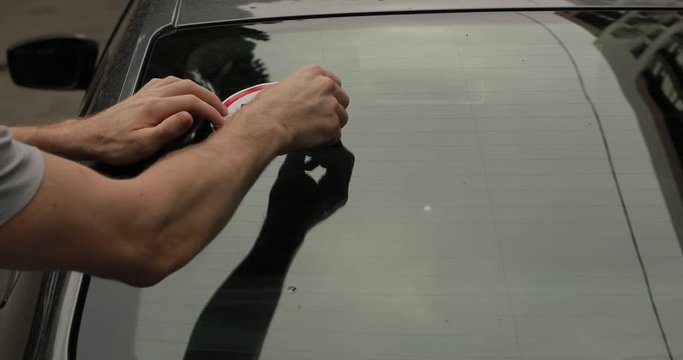 Beginner driver attaches a sign 70 kmph on a back window of his car, newbie glue speed limit sticker