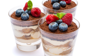Classic tiramisu dessert with blueberries and raspberries in a glass isolated on a white background with clipping path