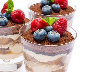Classic tiramisu dessert with blueberries and raspberries in a glass isolated on a white background with clipping path