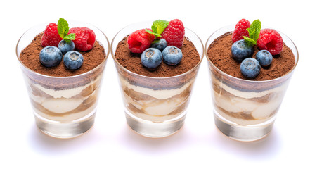 Classic tiramisu dessert with blueberries and raspberries in a glass isolated on a white background with clipping path