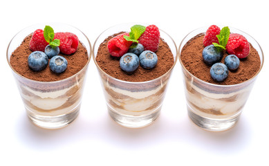 Classic tiramisu dessert with blueberries and raspberries in a glass isolated on a white background with clipping path