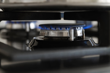Fototapeta na wymiar Gas burning from a kitchen gas stove. Blue gas flame on hob. Closeup, selective focus