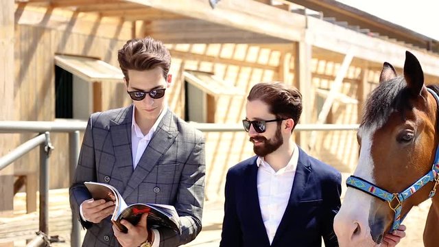 two businessmen standing near a horse
