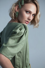Fashion portrait of blonde female model on grey background. stylish green clothes and accessories....