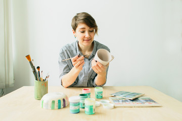 Fototapeta premium the pottery girl holds in hands a mug to paint the ornament