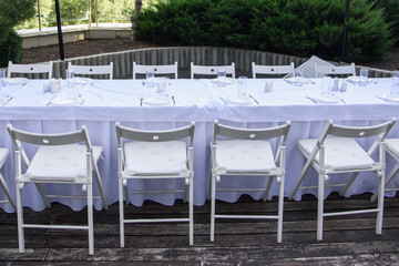 White served table outdoor on background of green trees