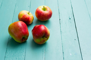 four apples on blue wooden background