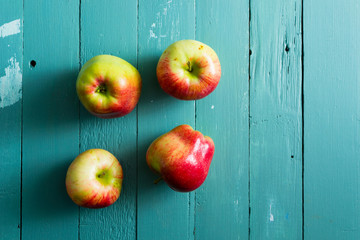 four apples on blue wooden background