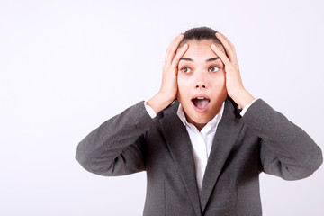 young woman standing over grey grunge wall crazy and mad shouting and yelling with aggressive expression and arms raised. Frustration