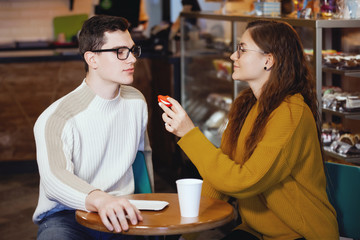 Two cute young men and a girl in a cafe.
