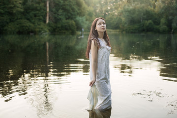 Young woman in nightie is standing in the river.
