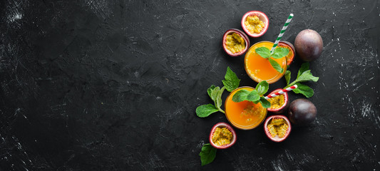 Passion fruits juice and fruit on a black background. Tropical Fruits. Top view. Free space for...