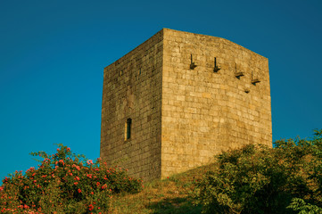 Stone square tower over rocky hill on sunset