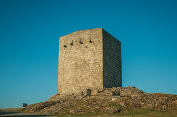 Naklejka premium Stone square tower over rocky hill on sunset