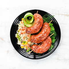 Baked sausages with rice. In a black plate. Top view. Free copy space.