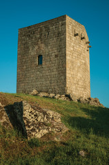 Fototapeta na wymiar Stone square tower over rocky hill on sunset