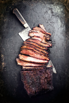 Traditional smoked barbecue wagyu beef brisket offered as top view with a knife on an old rustic board with copy space