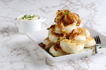 pile of pierogies with sour cream caramelized onions and a fork
