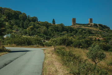 Road passing through hilly landscape with the towers of Castle