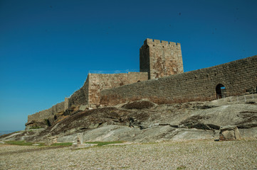 Fototapeta na wymiar Stone wall and square tower from castle over rocky hill