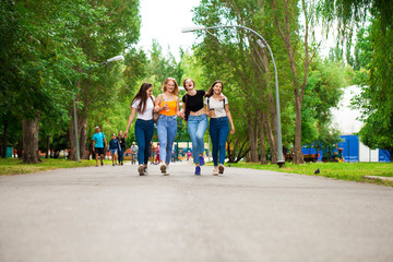 Fototapeta premium Happy women in blue jeans walking in summer park
