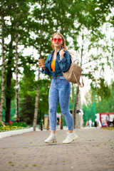 Young Blonde Girl in blue jeans walking in summer park