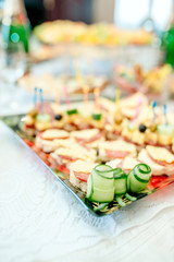 Candy bar. White wedding cake decorated by flowers standing of festive table with deserts, strawberry tartlet and cupcakes. Wedding. Reception Tartlets