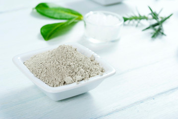 cosmetic clay and bath salt on white wooden table