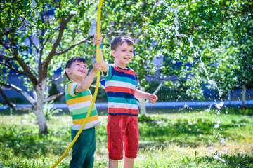 Obraz premium Brothers having fun splash each other with water in the village