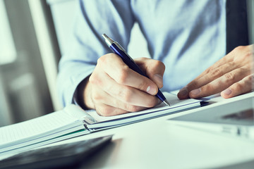 Businessman hand writing note on a notebook. Business man working at office desk. Close up of empty...