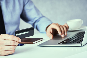 Businessman holding credit card and typing on laptop for online shopping and payment makes a purchase on the Internet.