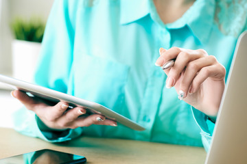 Business woman looking and studying statistics on tablet display closeup. Female left hand holds pen, right holds tablet.
