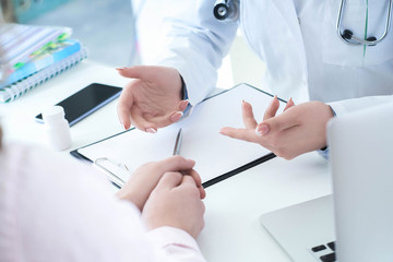 Female doctor explaining patient symptoms or asking a question as they discuss together in a consultation. Just hands over the table.