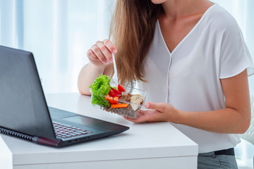 Healthy snack at office workplace. Business woman eating meals from lunch box at working table...