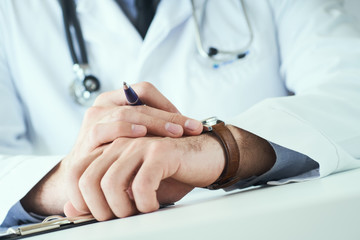 Man doctor with stethoscope looking at wrist watch. Doctor in white uniform at office background waiting for patients. Time to visit therapist.